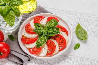 Canlı ve iştah açıcı bir Caprese antipasti. İçinde olgun domatesler, taze mozarella ve aromatik fesleğen yaprakları var.