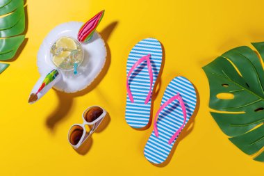 Canlı bir yaz tatili sahnesi. Terlikleri, gölgeleri ve parlak bir arka planda kokteyli olan yüzen bir flamingo. Neşeli ve tropikal bir atmosferi çağrıştırıyor.