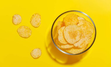 Parlak sarı bir zemin üzerine kurulmuş canlı bir patates cipsi sergilenen fotoğraf fotokopi uzayı ile eğlenceli ve iştah açıcı bir sahne yaratıyor.