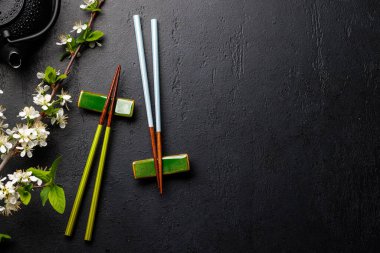 Kiraz çiçeği dalı ve yemek çubuklarıyla süslenmiş masa, Japon yemek kültürünün somut örneği, geniş bir kopya alanı sağlıyor.