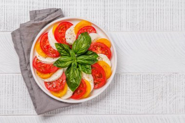 Canlı ve iştah açıcı bir Caprese antipasti sergisi içinde olgun domatesler, taze mozarella ve aromatik fesleğen yaprakları var. Kopyalama alanı olan düz