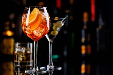 Bar masasında çeşitli kokteyller. Arka planda yanan şişelerin renkli bokeh 'i, dinamik ve canlı bir ortam yaratarak ortamı canlandırıyor.