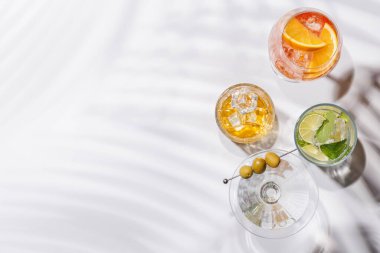 Parlak bir arka planda Aperol Spritz, Mojito ve Martini gibi canlı kokteyller sergilenmektedir. Karışımın ferahlatıcı ve renkli bir kutlaması