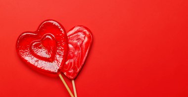 Kalp şeklindeki lolipoplar canlı kırmızı bir arkaplanda geniş bir fotokopi alanı ile düzenlenmiştir. Sevgililer Günü temaları için mükemmel, tatlılığı ve aşkı sembolize eder.