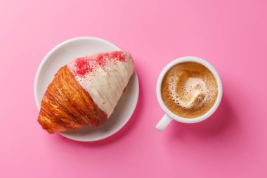 Nefis bir kahve ve ahudududulu kruvasan eşleşmesi, yumuşak pembe bir arka plan üzerine kurulmuş, rahat ve hoşgörülü bir an için mükemmel.