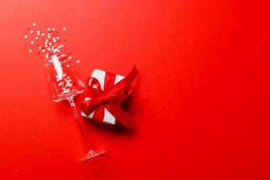 Kalp şeklinde bir dekorla süslenmiş kırmızı bir arka planda, Sevgililer Günü için sevgiyi ve kutlamayı simgeleyen bir şampanya kadehi.