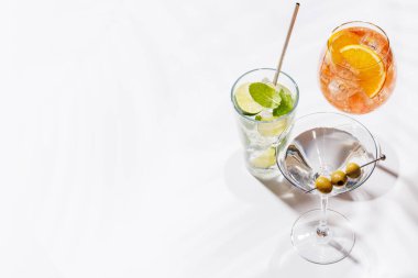 Parlak bir arka planda Aperol Spritz, Mojito ve Martini gibi canlı kokteyller sergilenmektedir. Karışımın ferahlatıcı ve renkli bir kutlaması