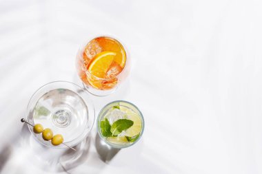 Parlak bir arka planda Aperol Spritz, Mojito ve Martini gibi canlı kokteyller sergilenmektedir. Karışımın ferahlatıcı ve renkli bir kutlaması