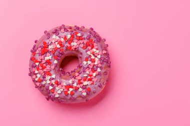 Pembe arka planda kalp şeklinde dekorla süslenmiş tatlı bir çörek. Sevgililer Günü kutlamaları için mükemmel. Sevdiklerimizle paylaşacağımız lezzetli ve şenlikli bir ziyafet.