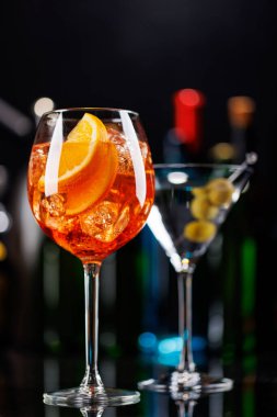 Bar masasında çeşitli kokteyller. Arka planda yanan şişelerin renkli bokeh 'i, dinamik ve canlı bir ortam yaratarak ortamı canlandırıyor.