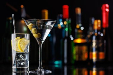 Bar masasında çeşitli kokteyller. Arka planda yanan şişelerin renkli bokeh 'i, dinamik ve canlı bir ortam yaratarak ortamı canlandırıyor.