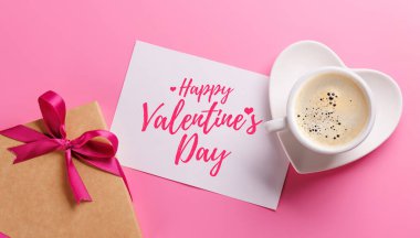 Romantik bir Sevgililer Günü hazırlığı. İçinde bir hediye kutusu ve dumanı tüten bir fincan kahve var. Sıcak ve tatlı bir ortam yaratıyor. Kopyalama alanı tebrik kartı ile düz uzandı