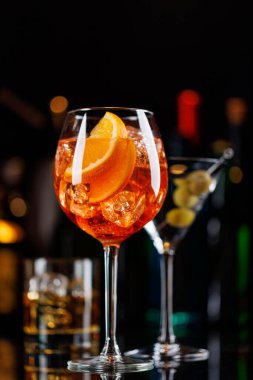 Bar masasında çeşitli kokteyller. Arka planda yanan şişelerin renkli bokeh 'i, dinamik ve canlı bir ortam yaratarak ortamı canlandırıyor.