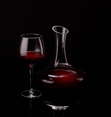 Kırmızı şarabın bir bardakta ve sürahide sunumu koyu bir arka planda, entelektüellik ve zenginlik yayıyor.