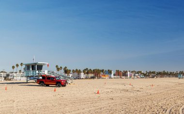 Classic lifeguard tower paired with a rescue vehicle parked nearby on a sandy beach under a clear blue sky. A timeless scene capturing the essence of beach safety and coastal life clipart