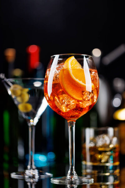 Various cocktails on a bar table. The colorful bokeh of illuminated bottles in the background enhances the mood, creating a dynamic and lively ambiance