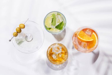 Parlak bir arka planda Aperol Spritz, Mojito ve Martini gibi canlı kokteyller sergilenmektedir. Karışımın ferahlatıcı ve renkli bir kutlaması