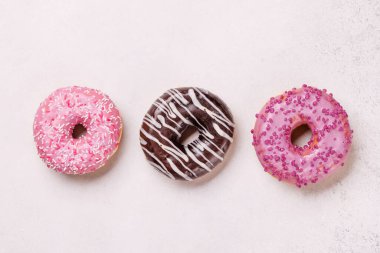 Değişik malzemelerle dolu renkli bir donut çeşidi. Oyuncak düz bir zeminde taş bir arka planda düzenlenmiş.