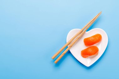 Yemek çubukları eşliğinde lezzetli suşilerle dolu kalp şeklinde bir tabak. Japon mutfağını sembolize ediyor.