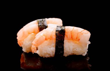 Suşi güzel düzenlenmiş, taze malzemeler ve canlı renkler içeriyor, temiz siyah bir arka planda.