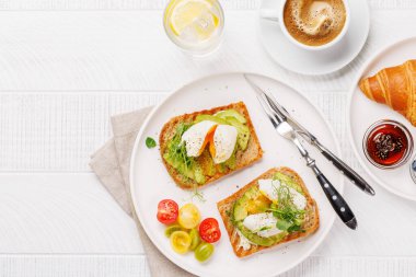 Lezzetli avokado tostlarıyla kahvaltı mükemmel pişmiş yumurta ve böğürtlenli gevrek kruvasan ve reçelli