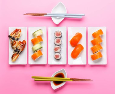 Çeşitli suşi ve maki dürümleri, taze malzemeler ve canlı renkler içeren tabaklar üzerinde güzelce düzenlenmiştir.