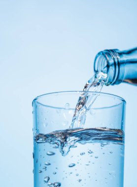 Şeffaf bardağa buzla doldurulan kristal berrak su canlandırıcı kabarcıklar ve kabarcıklar yaratır. Su ve saflığın mükemmel bir temsili.