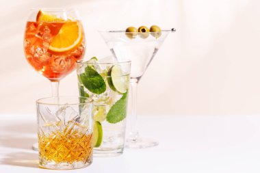 Parlak bir arka planda Aperol Spritz, Mojito ve Martini gibi canlı kokteyller sergilenmektedir. Karışımın ferahlatıcı ve renkli bir kutlaması