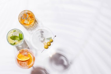Parlak bir arka planda Aperol Spritz, Mojito ve Martini gibi canlı kokteyller sergilenmektedir. Karışımın ferahlatıcı ve renkli bir kutlaması