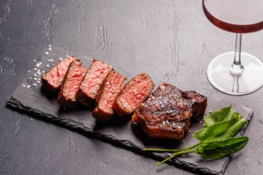 Mükemmel pişirilmiş çizgili biftek sulu, yumuşak bir dokuya sahip koyu arkaplanda kırmızı şarapla eşleştirilmiş. Biftek ve şarap aşıkları için gurme yemeği