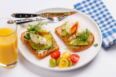 Lezzetli avokado tostları mükemmel pişirilmiş haşlanmış yumurtalarla, sağlıklı ve besleyici bir yemek için çıtır ekmekle servis edilir.