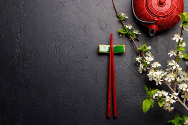Kiraz çiçeği dalı ve yemek çubuklarıyla süslenmiş masa, Japon yemek kültürünün somut örneği, geniş bir kopya alanı sağlıyor.
