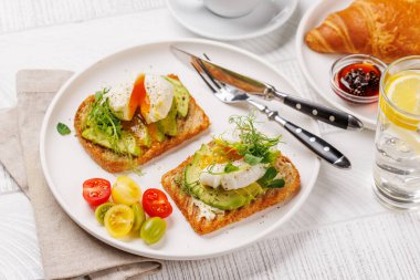 Lezzetli avokado tostlarıyla kahvaltı mükemmel pişmiş yumurta ve böğürtlenli gevrek kruvasan ve reçelli