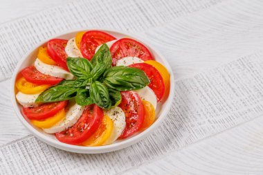 Canlı ve iştah açıcı bir Caprese antipasti. İçinde olgun domatesler, taze mozarella ve aromatik fesleğen yaprakları var.