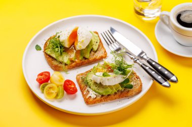 Lezzetli avokado tostları mükemmel pişirilmiş haşlanmış yumurtalarla, sağlıklı ve besleyici bir yemek için çıtır ekmekle servis edilir.