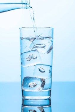 Şeffaf bardağa buzla doldurulan kristal berrak su canlandırıcı kabarcıklar ve kabarcıklar yaratır. Su ve saflığın mükemmel bir temsili.