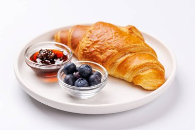 Lezzetli bir kahvaltı ya da atıştırmalık olarak taze yaban mersinli ve yanında tatlı böğürtlen reçelli gevrek altın kruvasan.