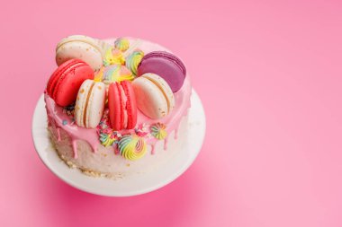 Renkli badem kurabiyeleri ve canlı süslemelerle süslenmiş güzel dekore edilmiş bir pasta. Görsel olarak çekici ve lezzetli bir tatlı yaratıyor. Kutlamalar ve özel durumlar için mükemmel.