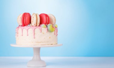 Renkli badem kurabiyeleri ve canlı süslemelerle süslenmiş güzel dekore edilmiş bir pasta. Görsel olarak çekici ve lezzetli bir tatlı yaratıyor. Kutlamalar ve özel durumlar için mükemmel.