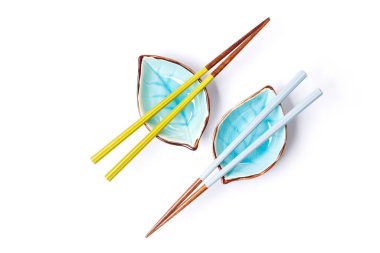 Bir suşi çubuğu ve küçük bir kase, temiz beyaz bir zemin üzerine yerleştirilmiş, geleneksel Japon yemek elementlerini sergiliyor.