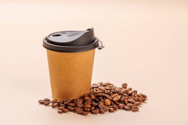 Zengin, aromatik kavrulmuş kahve çekirdekleri ile çevrili taze demlenmiş kağıt bir fincan kahve. Sıcaklığın, enerjinin ve kafeine olan sevginin mükemmel bir temsili.