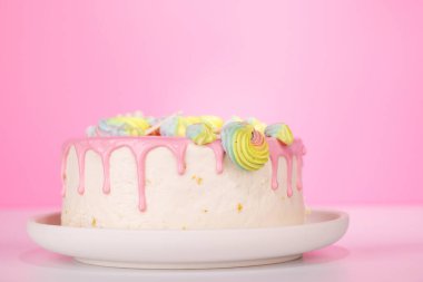 Renkli badem kurabiyeleri ve canlı süslemelerle süslenmiş güzel dekore edilmiş bir pasta. Görsel olarak çekici ve lezzetli bir tatlı yaratıyor. Kutlamalar ve özel durumlar için mükemmel.