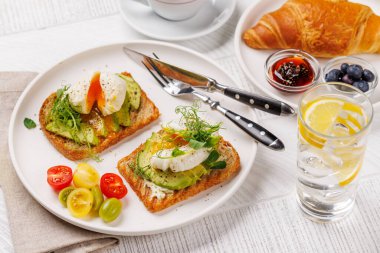 Lezzetli avokado tostlarıyla kahvaltı mükemmel pişmiş yumurta ve böğürtlenli gevrek kruvasan ve reçelli