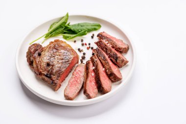 Beyaz arka planda sulu, yumuşak bir dokusu olan mükemmel pişirilmiş çizgili biftek. Biftek ve şarap aşıkları için gurme yemeği