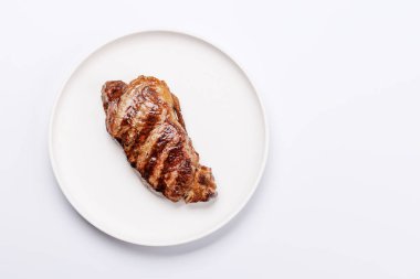 Beyaz arka planda sulu, yumuşak bir dokusu olan mükemmel pişmiş çizgili biftek. Biftek ve şarap aşıkları için gurme yemeği