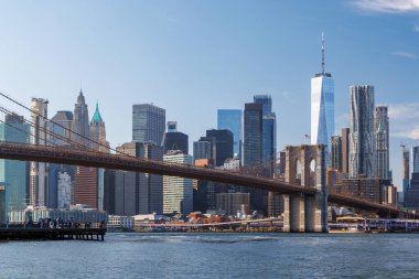 Manhattan 'ın ufuk çizgisine uzanan ikonik Brooklyn Köprüsü' nün çarpıcı panoramik görüntüsü, berrak gökyüzü altında zamansız mimari güzelliğini ve şehir cazibesini yakalıyor.