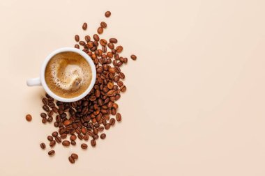 Zengin, aromatik kavrulmuş kahve çekirdekleri ile çevrili buharda pişmiş bir fincan taze kahve. Sıcaklığın, enerjinin ve kafeine olan sevginin mükemmel bir temsili.