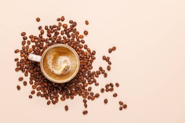 Zengin, aromatik kavrulmuş kahve çekirdekleri ile çevrili buharda pişmiş bir fincan taze kahve. Sıcaklığın, enerjinin ve kafeine olan sevginin mükemmel bir temsili.