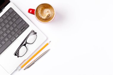 Dizüstü bilgisayar ve kahve fincanı içeren temiz ve minimal bir masa düzeni, tasarım veya metin için geniş bir kopya alanı sunar