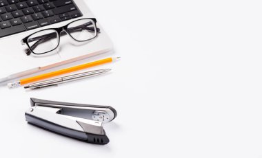 Dizüstü bilgisayar ve ofis malzemelerini içeren temiz ve minimal bir masa ayarlama, tasarım veya metin için geniş bir kopya alanı sunar